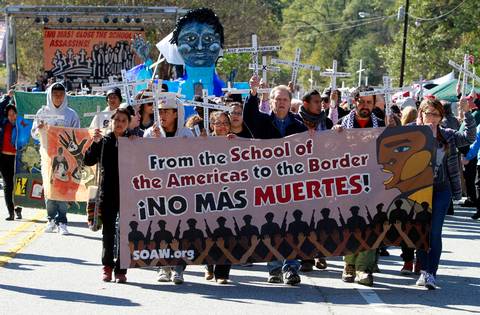 Mike Haskey mhaskey@ledger-enquirer.comFather Roy Bourgeois, front center, joins others in marching Sunday at the SOA Watch protest at the gates of Fort Benning. Bourgeois announced to the crowd that organizers have decided to move the protest from Columbus. 11/22/15